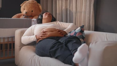 женщина отдыхает на диване положив руку на живот