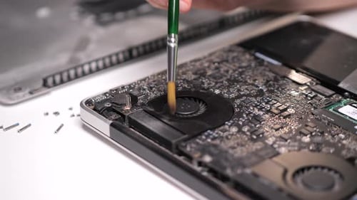 Technikerin reinigt Laptop-Kühlsystem mit Bürste