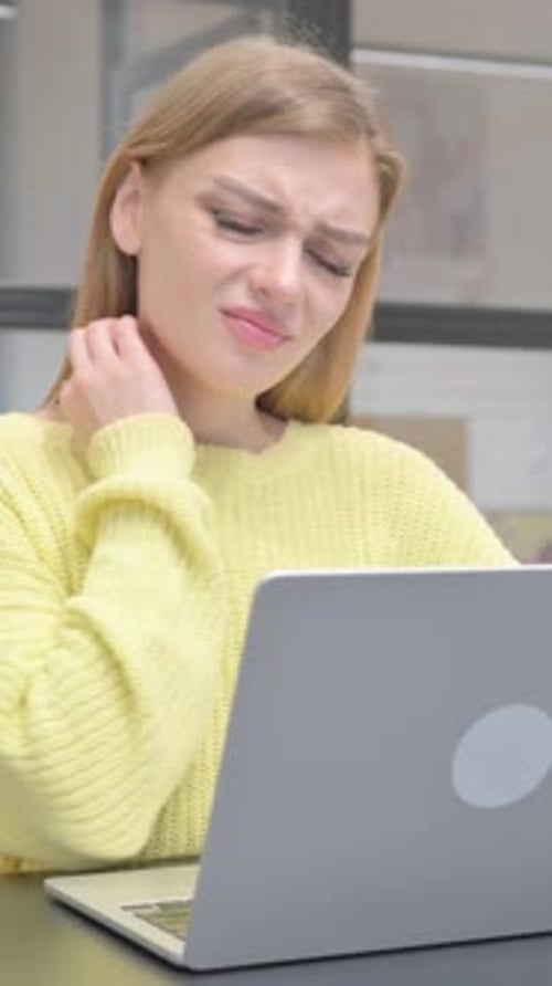 Woman Using Laptop Massaging Stiff Neck Indoors