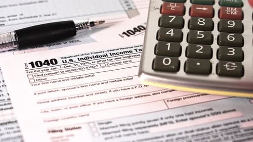 Person are seen working on U.S. income tax 1040 forms