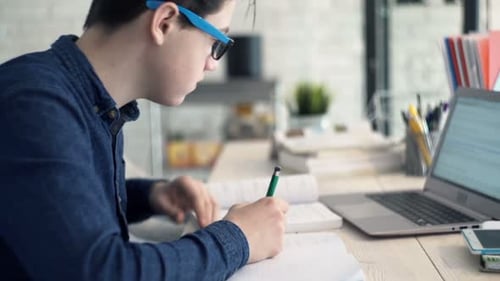 Teenager Studying, Writing in Notebook, Using Laptop