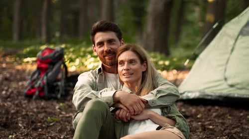 Couple Enjoys Outdoor Camping Experience in Forest With Tent and Backpacks Nearby