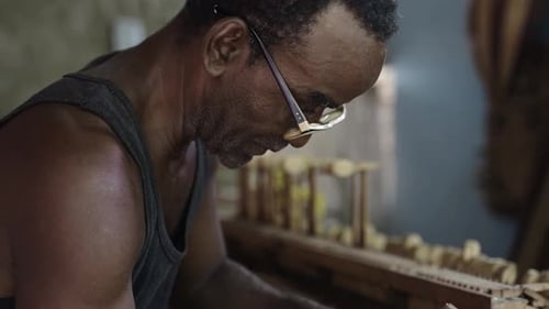 Man Crafts Wooden Boat Model in Workshop