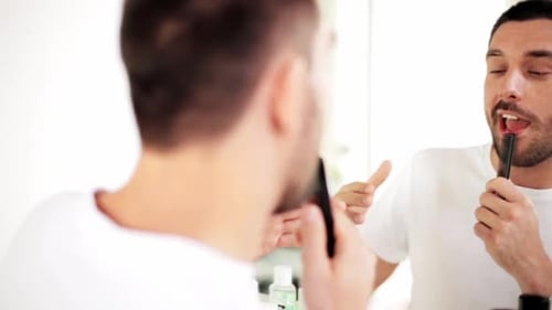 Man combs his beard in the mirror