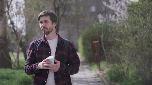 Cheerful Man Holding Coffee Cup Outdoors Smiling on Sunny Street