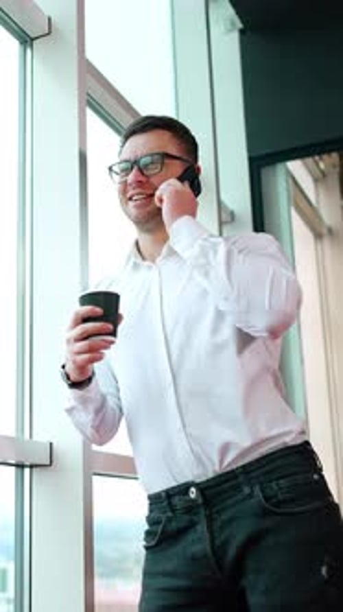 Relaxed smiling Caucasian male leaning on the window in office.