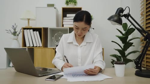 young woman working with document and laptop at home office