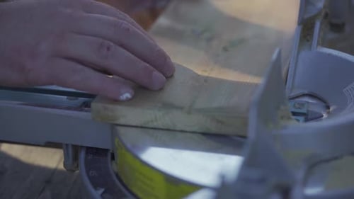Slow motion, man preparing to saw wooden plank with mitre saw in workshop. Close up