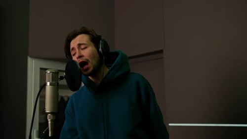 singer with headphones and microphone emotionally recording a new song in a professional studio