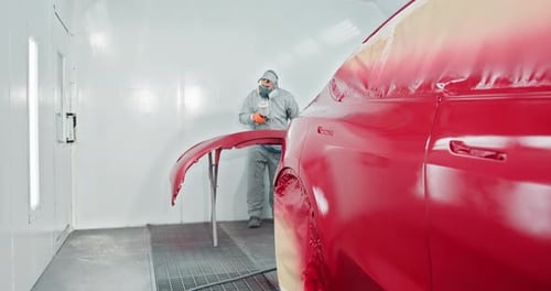 Car Painter Repairing and Painting Red Automobile in Service Chamber