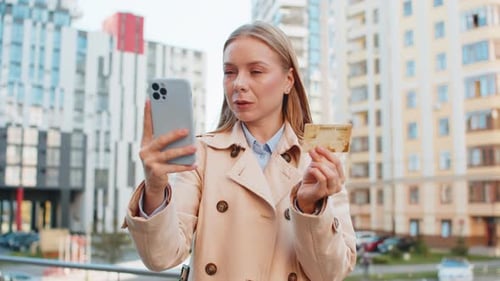 Caucasian Businesswoman Using Credit Card and Smartphone Shopping Online on Downtown City Street