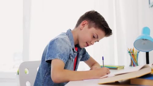 Boy Writes at Desk Doing Homework Inside Bright Room