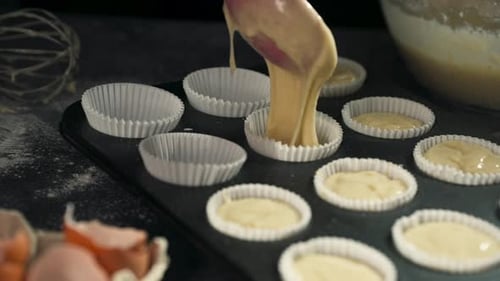 Filling cupcake liners with batter for baking using delicate ladle, slow motion process