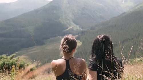 Portrait Two of Tourist Women Sitting on the Top of Mountain and Look at the Scenery View