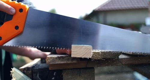 Hand pressing saw on wood plank, super slow motion at fps, woodworking focus, scattering