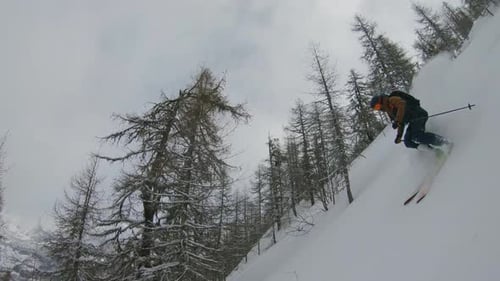Follow cam faceshot of freeride skier with snow spray in storm Swiss Alps