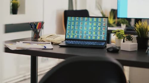 Desk with Financial Data on Laptop Screen