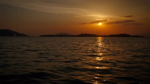 Nightfall sun on calm lake waves.