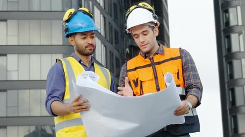 Zwei Bauingenieure überprüfen die Informationen aus dem Bauplan in Teamarbeit, Projektleiter planen