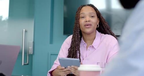 Segurando o tablet, mulher discutindo o trabalho com colegas em reunião de escritório