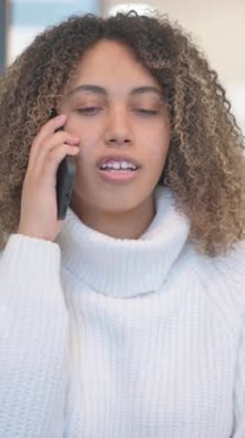 Woman in White Sweater Talking on Phone Indoors