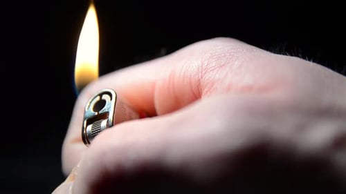 Gros plan d'une main d'homme allumant un briquet