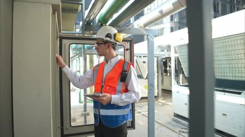 Engineer Inspects Equipment with Tablet and Radio