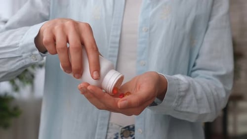 Adult Woman Pours Capsules into Hand