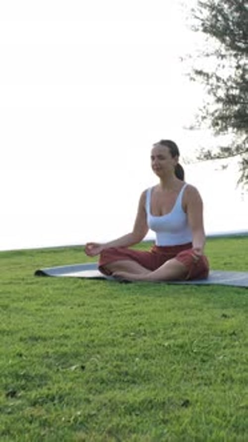Woman Meditating Outdoors on Tropical Green Grass