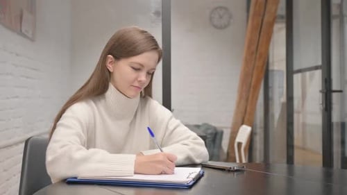 Woman Writing on Notepad at Table Indoors