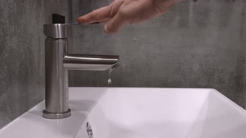 Dripping water faucet close up: plumbing issues and water conservation