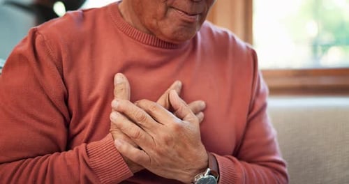 Heart attack, hands and senior man on sofa with lungs, problem or breathe