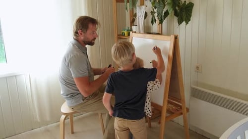 Father Helping Two Children Drawing on White Board