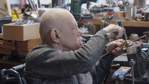 Senior Elderly Master Jeweler in Wheelchair Works in a Workshop