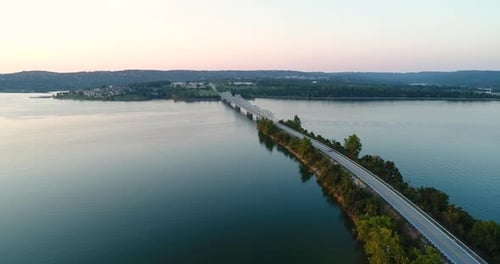 Voo aéreo sobre uma ponte e rodovia que se estende por paisagens cênicas