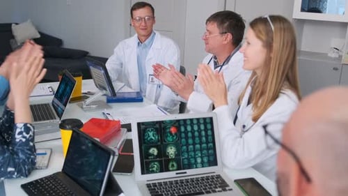 Doctors Applauding Colleague at Recognition Meeting in Medical Office