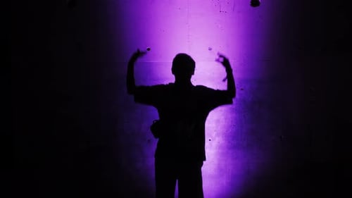 Silhouette Juggling Performance in Purple Light