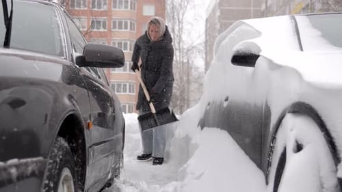 An aged woman works tirelessly in wintery courtyard environment
