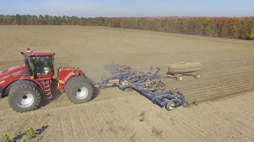 Big red combine working on the field cultivating and applying nitrogen ASP