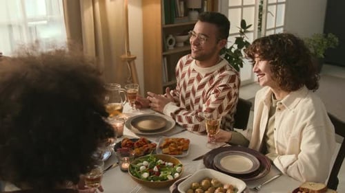 Four Friends, Smiling and Toasting, Enjoying Cozy Meal Together