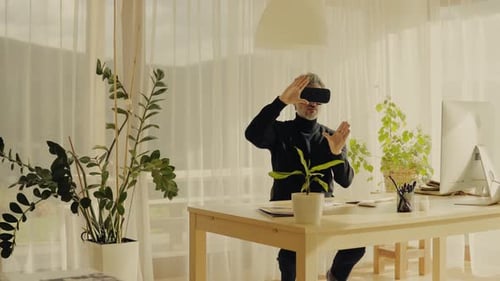 Mature man explores virtual reality with vr goggles in his home office