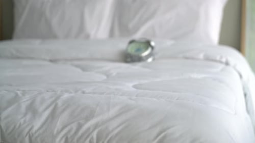 Alarm Clock on a Pristine Bed in Bedroom