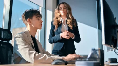 Business session in an office. Young man is using computer and discussing business affairs. Slow mot