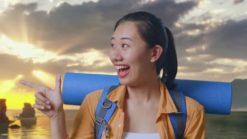 Close Up Of Asian Female Hiker Smiling And Pointing To Side on Beach