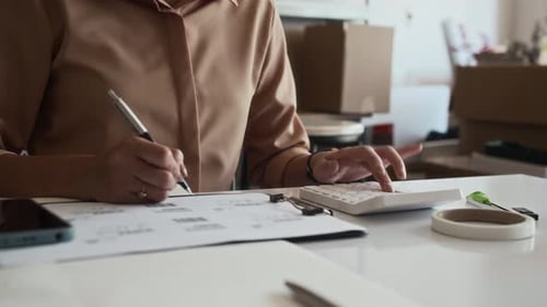 Woman Calculates Finances at Desk with Paperwork