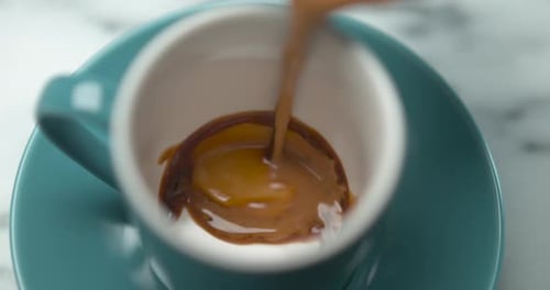 Pouring Rich Coffee into Blue Cup