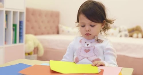 Young Child Cutting Paper with Scissors at Table