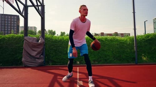 a Tall guy basketball player with the ball shows his dribbling skills during practice on the court