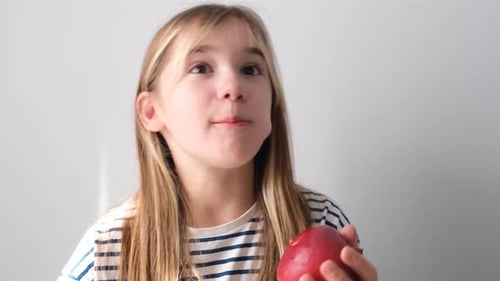 Nettes kleines Mädchen isst einen großen roten saftigen Apfel