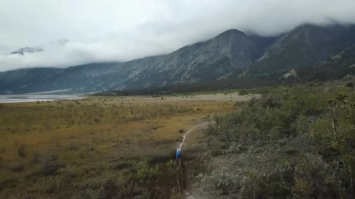 Hiker with a dog on a trail in a remote valley of the Yukon